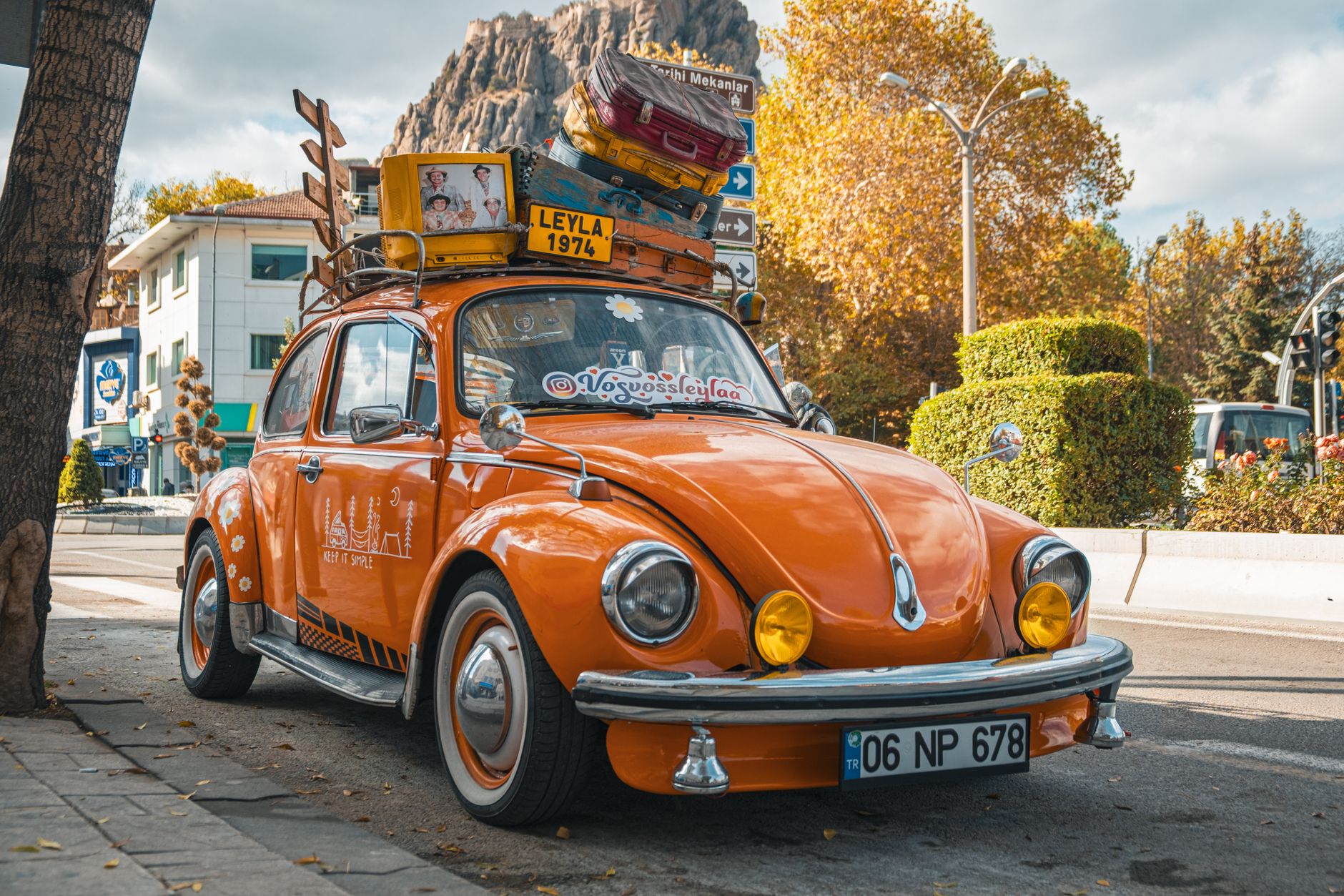 Orange Volkswagen Beetle parked on a vibrant street in Afyonkarahisar, Türkiye, showcasing retro charm.