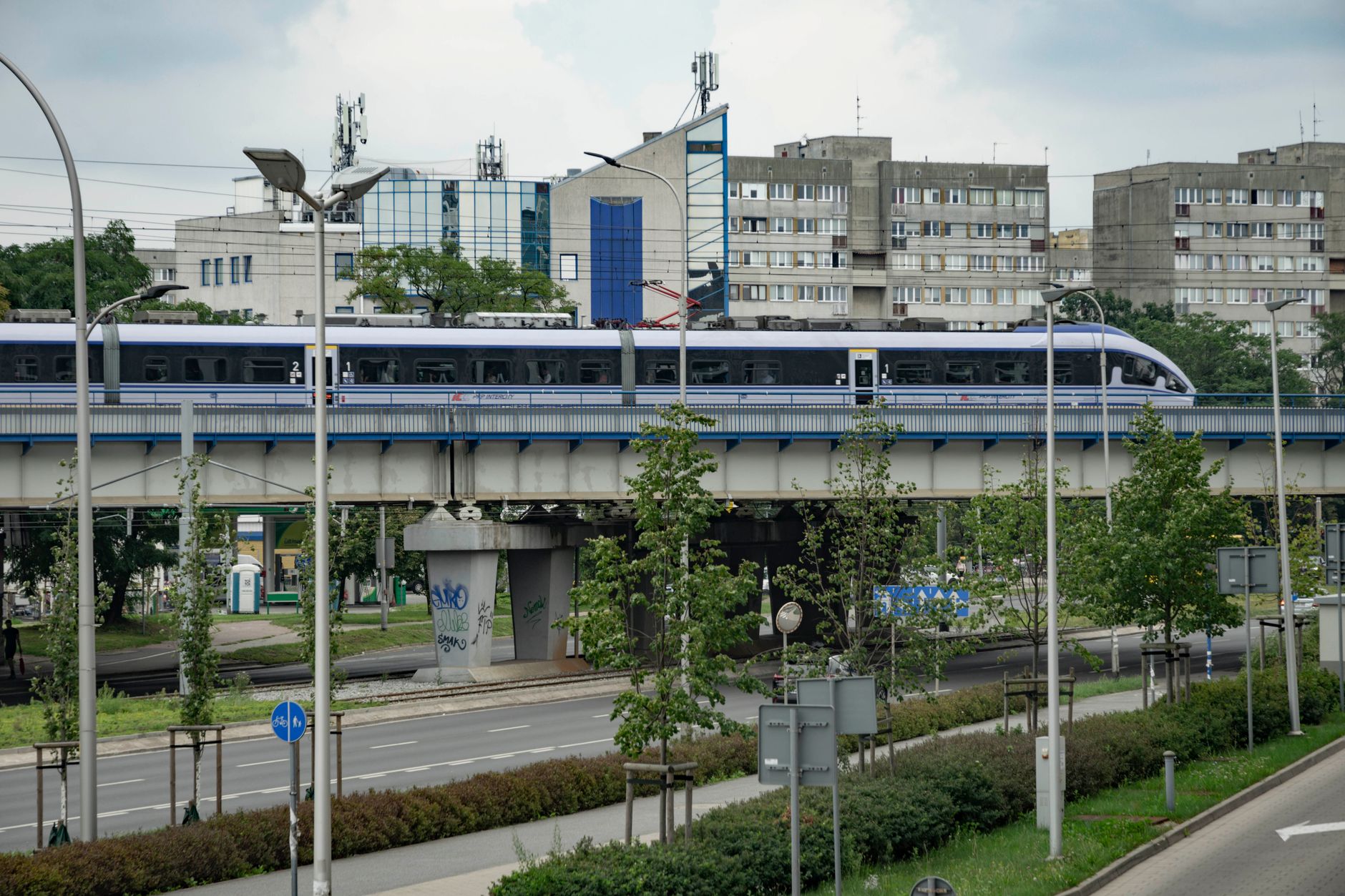 A sleek modern train travels across an urban overpass in Wrocław, Poland.