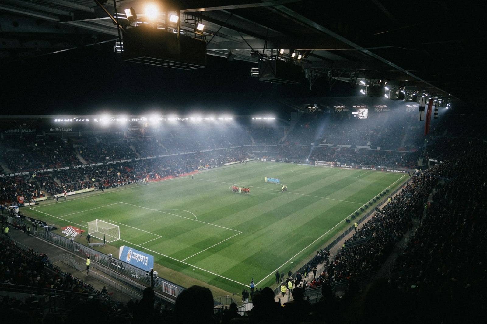 Rozświetlony nocą stadion piłkarski wypełniony kibicami